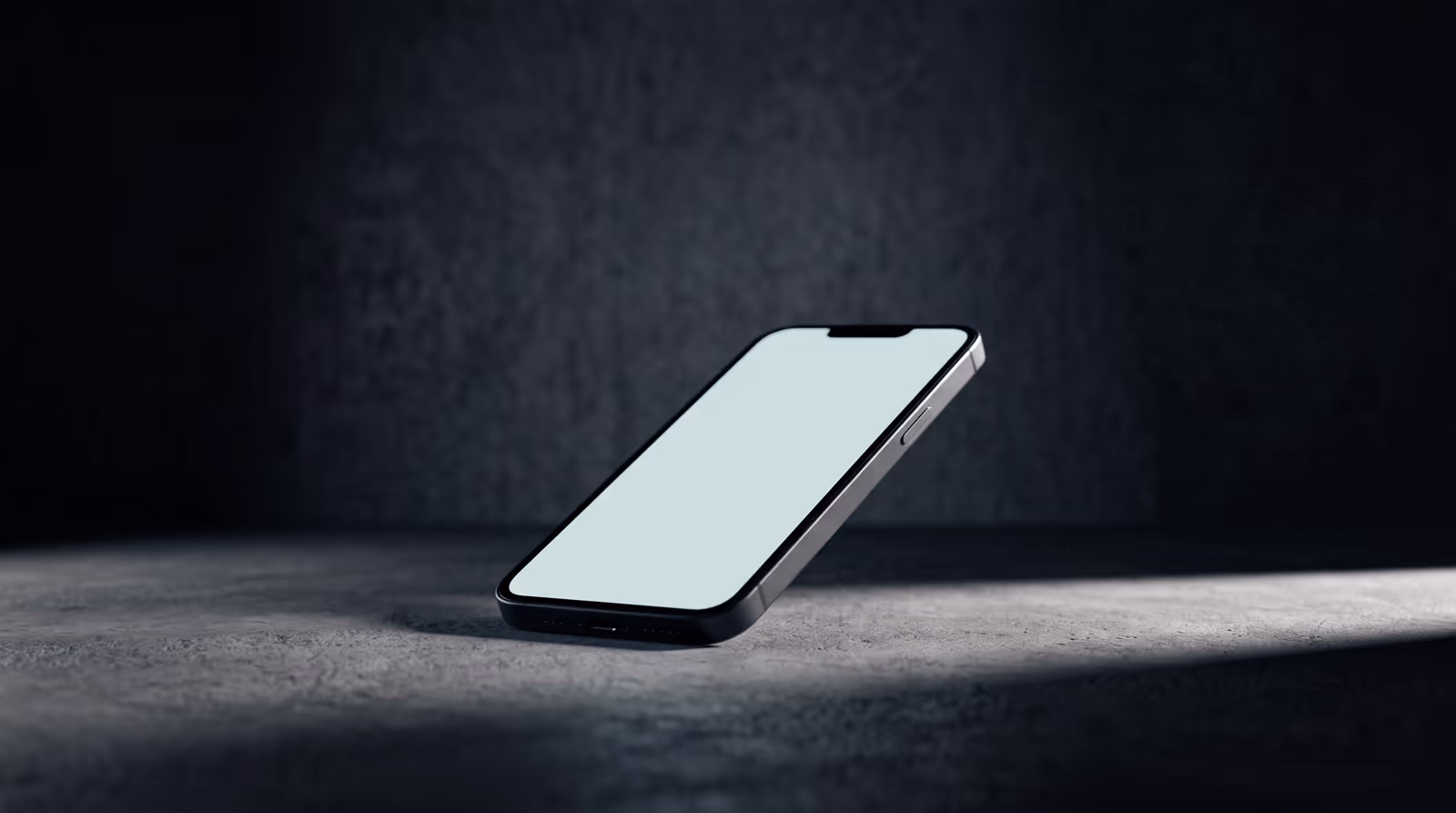 A phone lying on a concrete surface, its screen glowing faintly