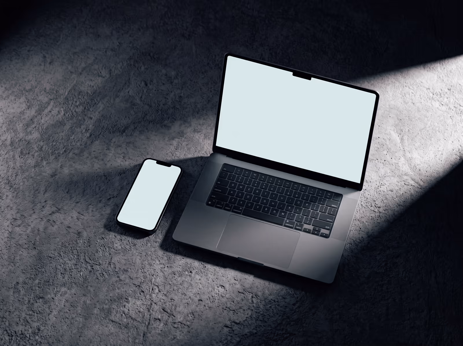 A phone and a laptop side by side, both screens lit