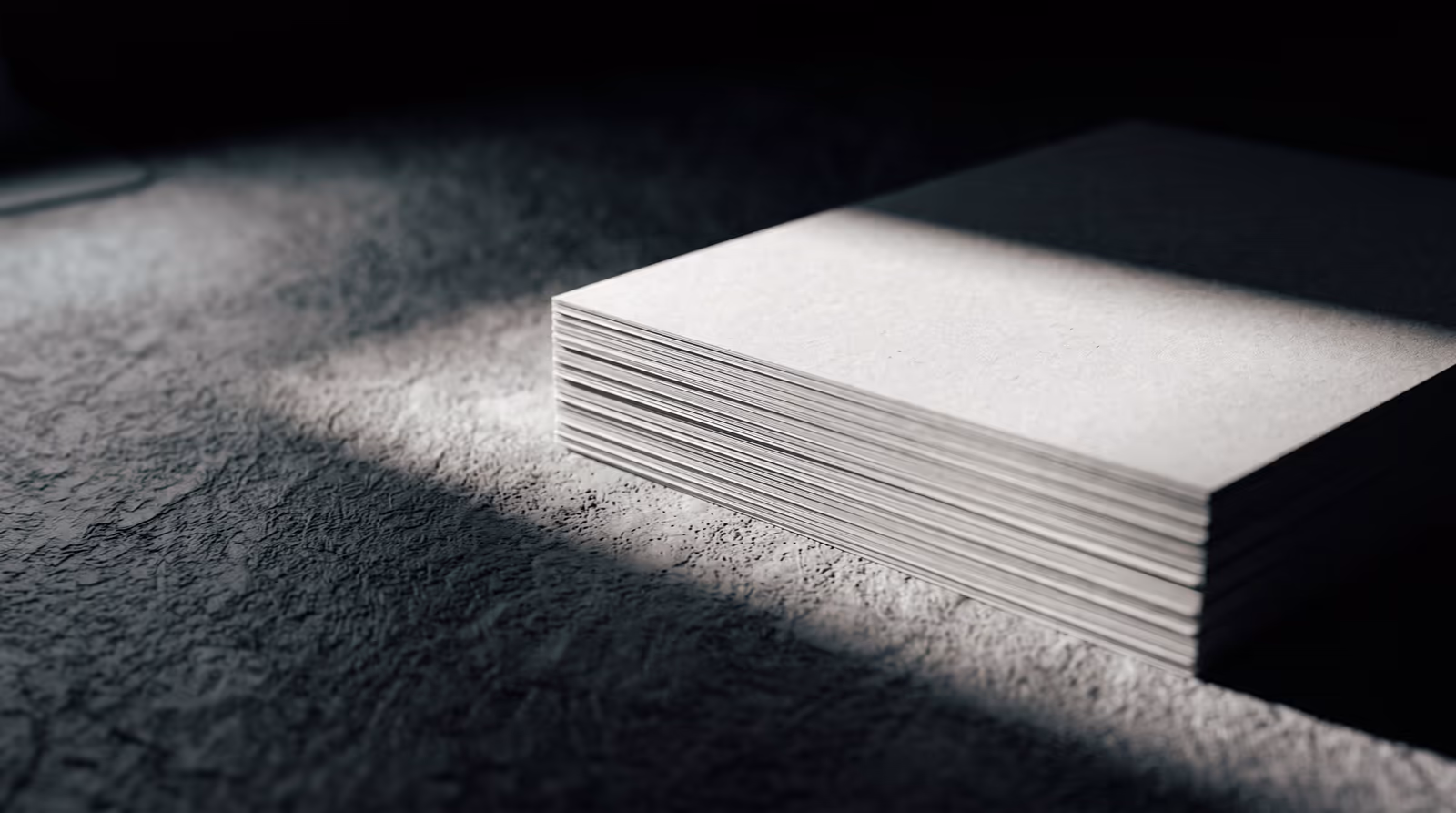 Stacked raw paper sheets under raking light