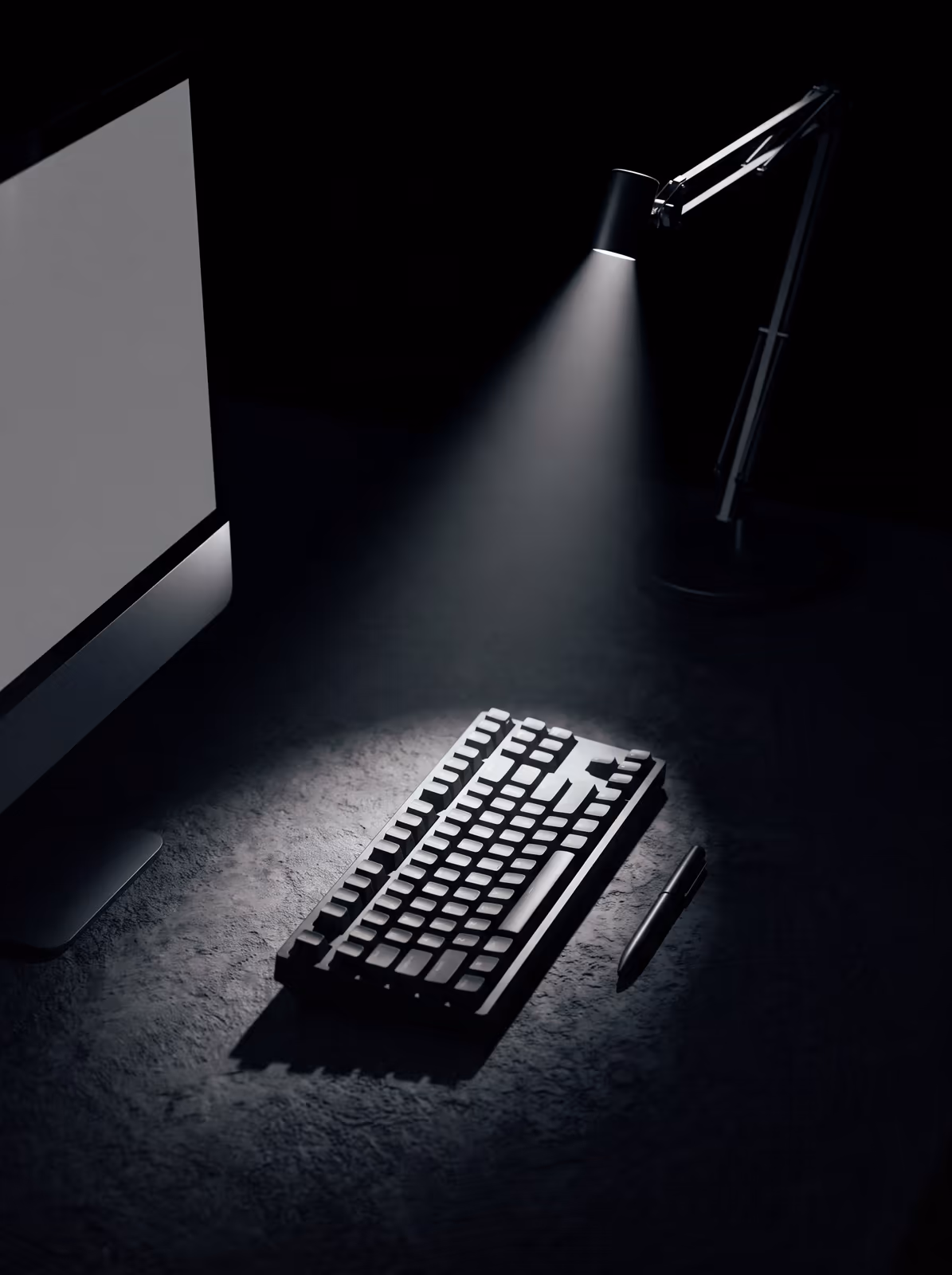 A desk monitor and keyboard lit by a single lamp